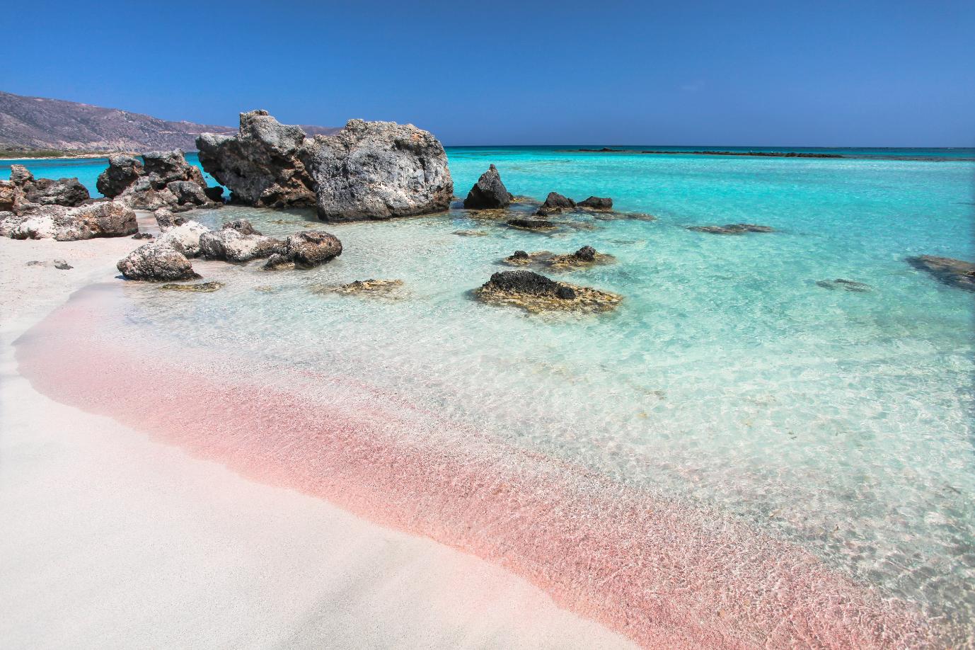 Shallow turquoise water and soft pale sand at a beach in Chania, Crete